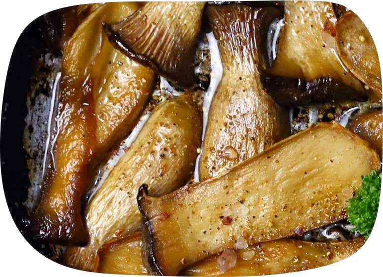 Lâminas longas de eryngui douradas e crocantes em uma frigideira escura.