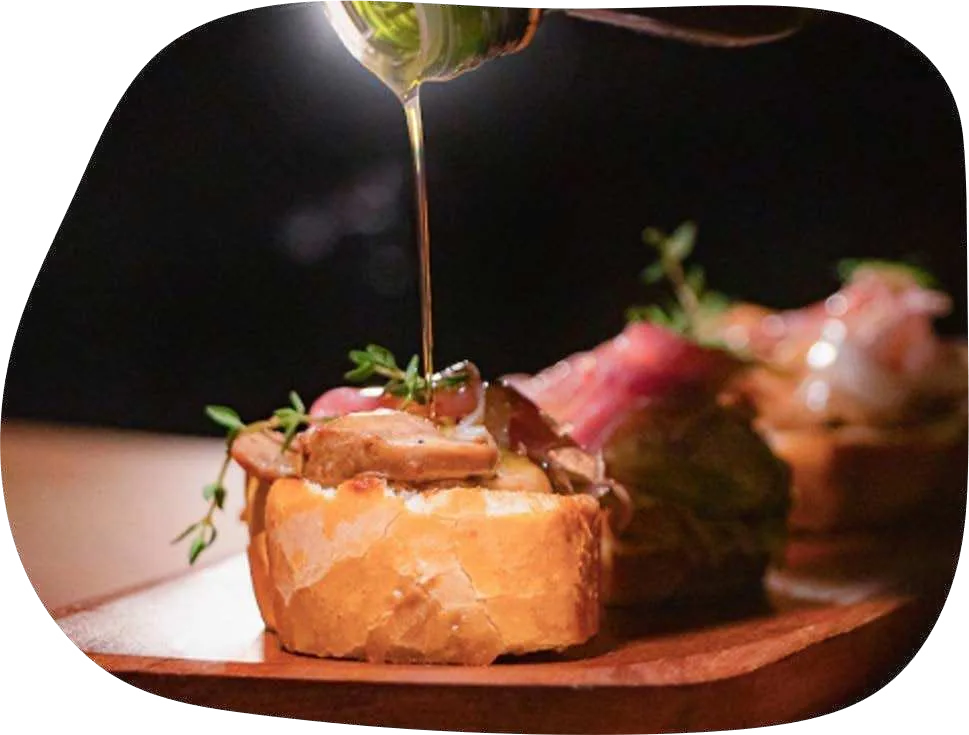 Bruschetta de pão rústico coberta com cogumelos, recebendo um fio de azeite.