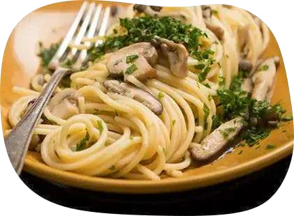 Espaguete com cogumelos fatiados e salsinha picada em prato amarelo, com garfo.