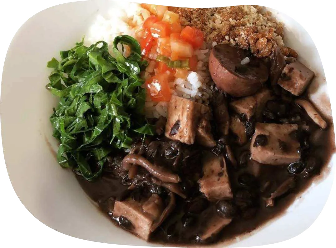 Prato de feijoada com cubos de tofu e cogumelos, couve, arroz, farofa e vinagrete.