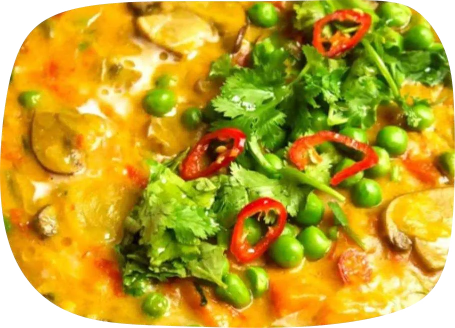 Moqueca alaranjada com cogumelos, ervilhas, coentro fresco e rodelas de pimenta vermelha.