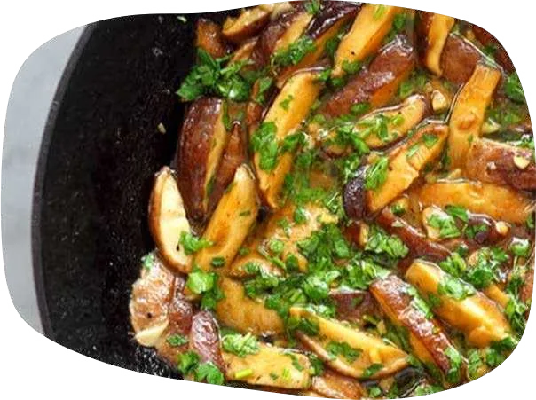 Tiras de shitake douradas na manteiga com salsinha picada em frigideira de ferro.