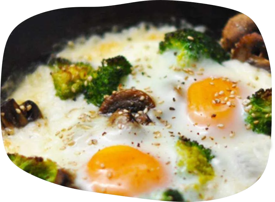 Skillet com ovos de gema mole, brócolis e cogumelos Paris sob queijo derretido.