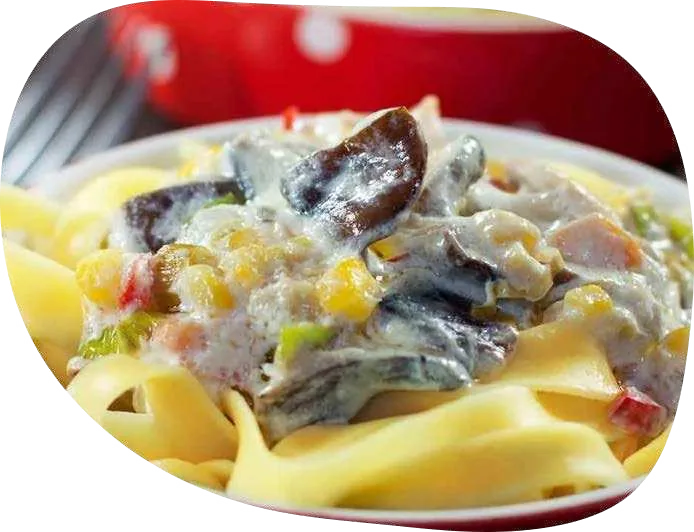 Tagliatelle com molho cremoso de shiitake e milho em prato branco.